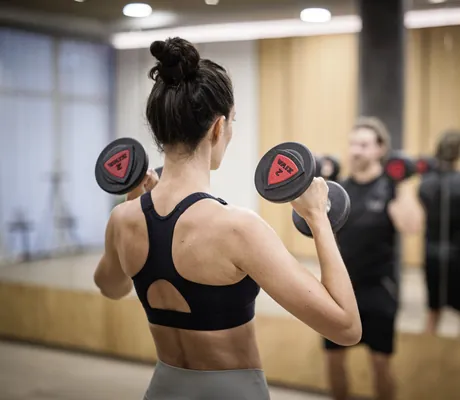 Junge Frau in sportlichem Outfit trainiert im Hotel Winkler mit Hanteln