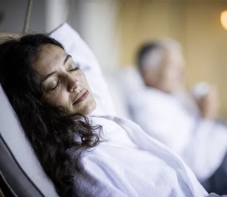 Dunkelhaarige Frau liegt mit geschlossenen Augen auf der Ruheliege im Hotel Winkler