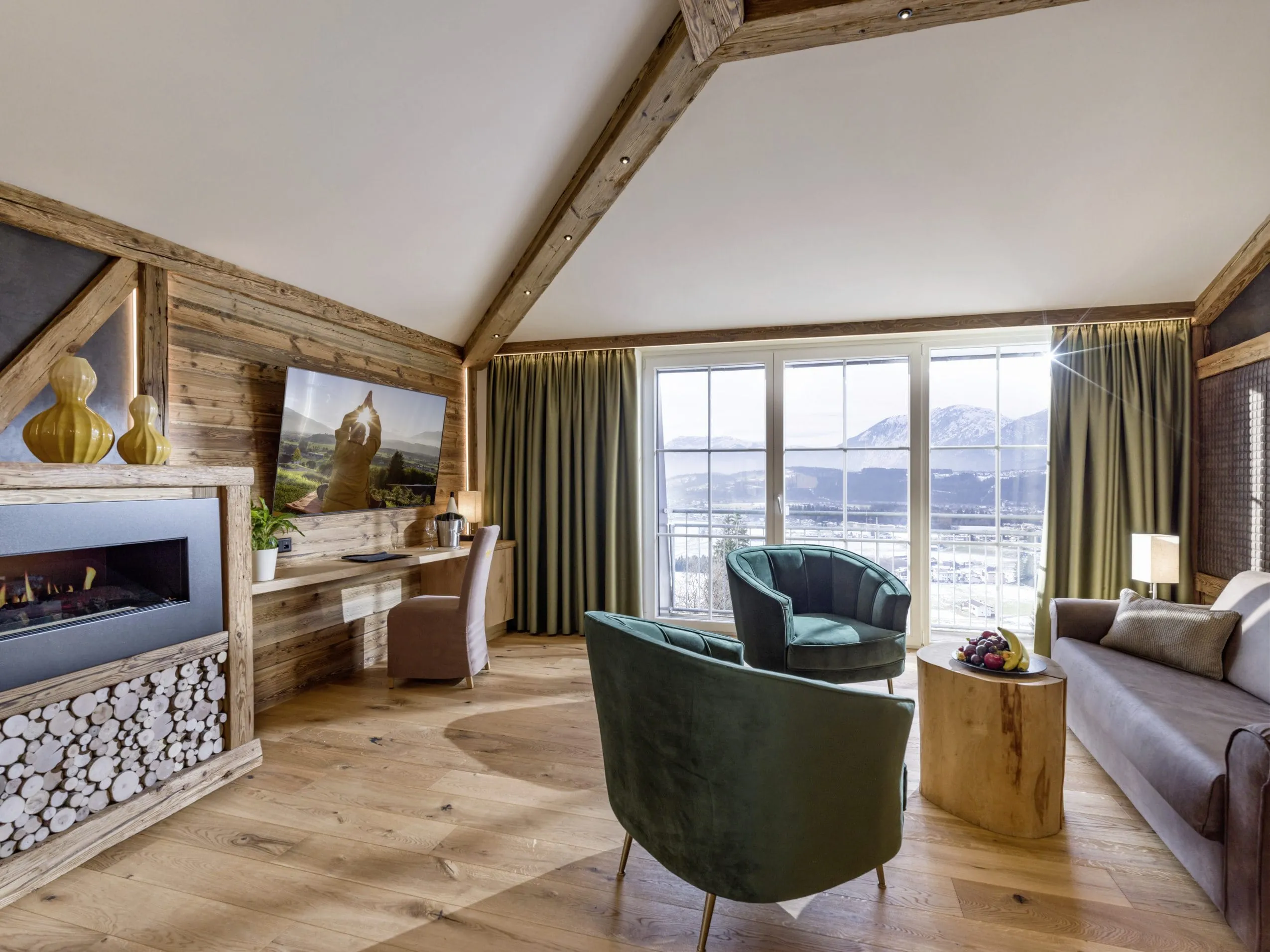 Suite im Panorama Royal mit gr&uuml;nen Sesseln und Holzofen-Kamin