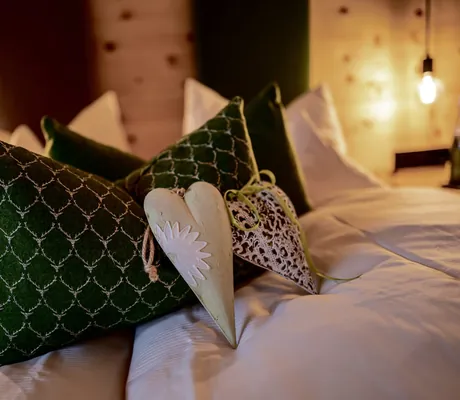 Kissen und Dekoherzen auf dem Bett im Hotel Alpenblick Ohlstadt