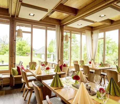 mit grünen und beigen Servietten eingedeckte Tische im Restaurant des Hotel Alpenblick Ohlstadt