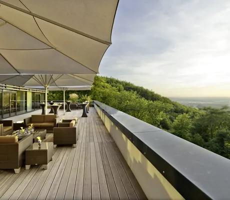 Loungemöbel unter beigen Sonnenschirmen auf der Terrasse mit Blick über die Wipfel im Lufthansa Seeheim