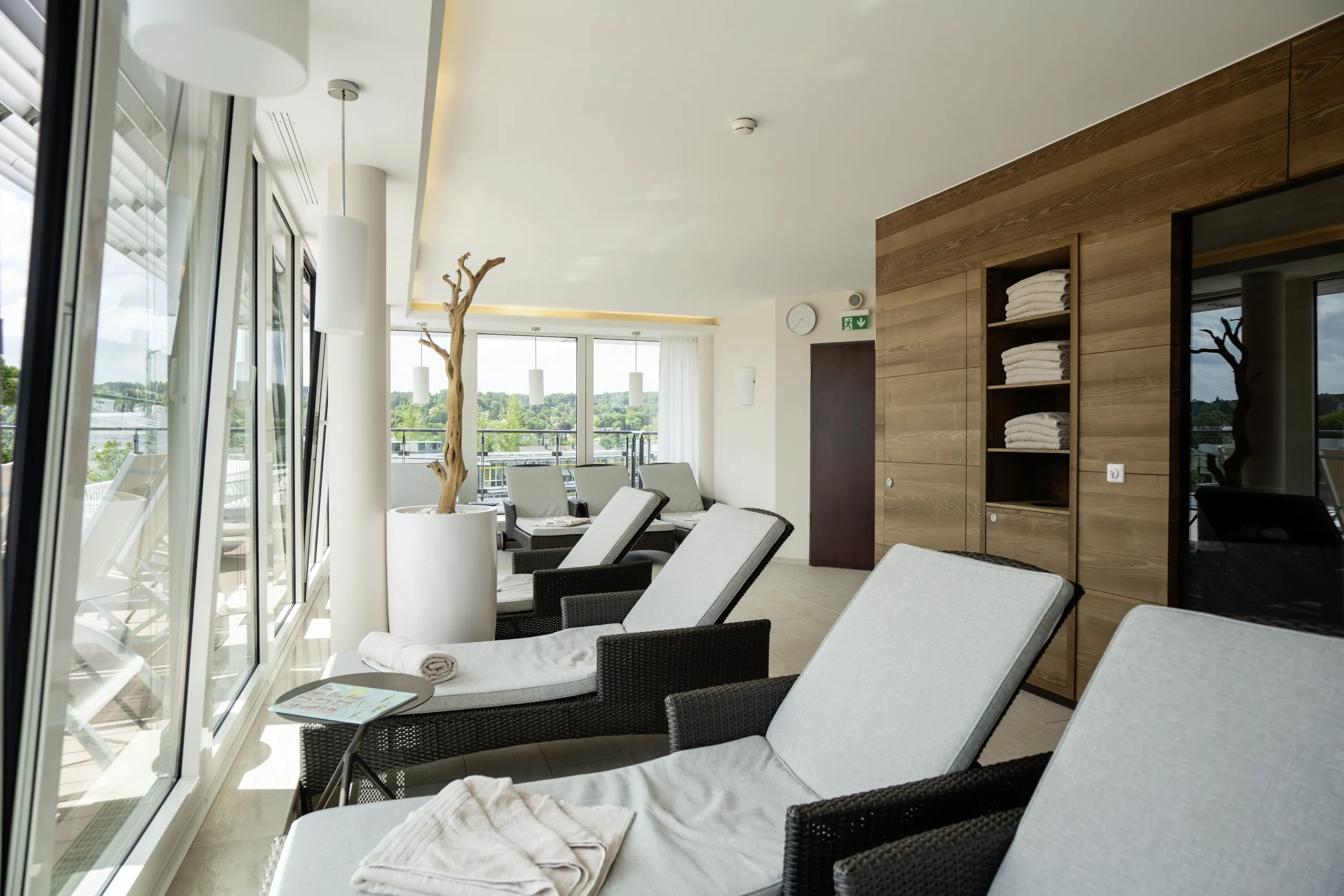 Heller Wellnessbereich des Hotel Vier Jahreszeiten Starnberg mit mehreren Ruheliegen mit Handt&uuml;chern und hellgrauen Polstern