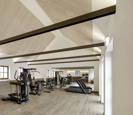 Heller Fitnessraum im Hotel Winkler Bräu mit mehreren Geräten und offenen Dachbalken aus Stahl