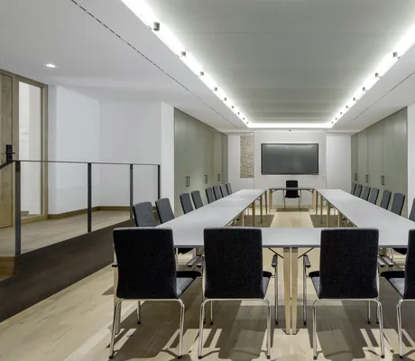 Moderner Tagungsraum im Hotel Winkler Bräu mit dunkelgrauen Stühlen in U-Form angeordnet, hohen Schränken und einem Bildschirm