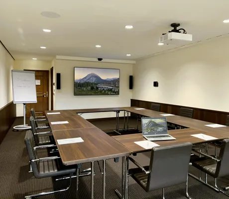 In U-Form augestellte Tagungstische im Boardingroom des Interalpen-Hotel Tyrol in Holzoptik