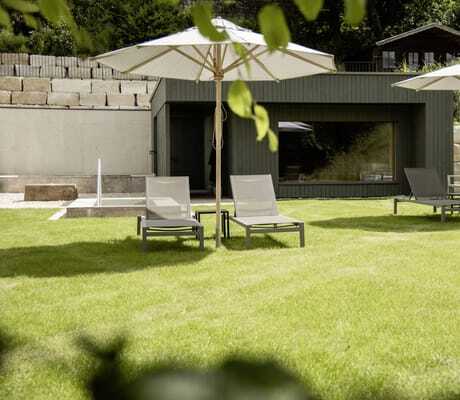 Liegewiese des Hotel Winkler Bräu mit Liegestühlen und weißen Sonnenschirmen