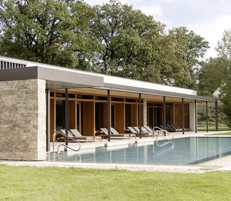Outdoorpool des Hotel Winkler Bräu mit Sonnenliegen und Hotelfassade im Hintergrund