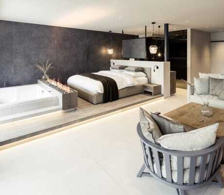 Suite im PURMONTES Private Luxury Chalet mit Leinensofa und im Wohnbereich integrierter Wanne