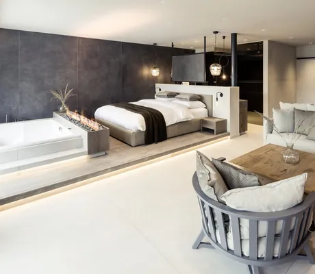 Suite im PURMONTES Private Luxury Chalet mit Leinensofa und im Wohnbereich integrierter Wanne