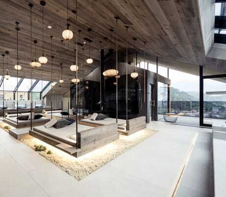 Loft Spa im PURMONTES Private Luxury Chalet mit an Seilen hängenden Holzliegen und asiatischen Lampen