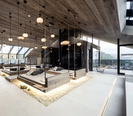 Loft Spa im PURMONTES Private Luxury Chalet mit an Seilen hängenden Holzliegen und asiatischen Lampen