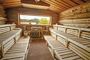 Kelosauna des Wellnesshotel Hofbräuhaus mit hellen Holzliegen, Natursteinboden und großem Fenster mit Blick in die Natur