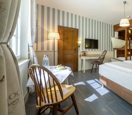 Familienzimmer im Bell Rock mit Doppelbett, Etagenbett in Bootsform, Schreibtisch, Tisch mit Stühlen und gestreifter Wand