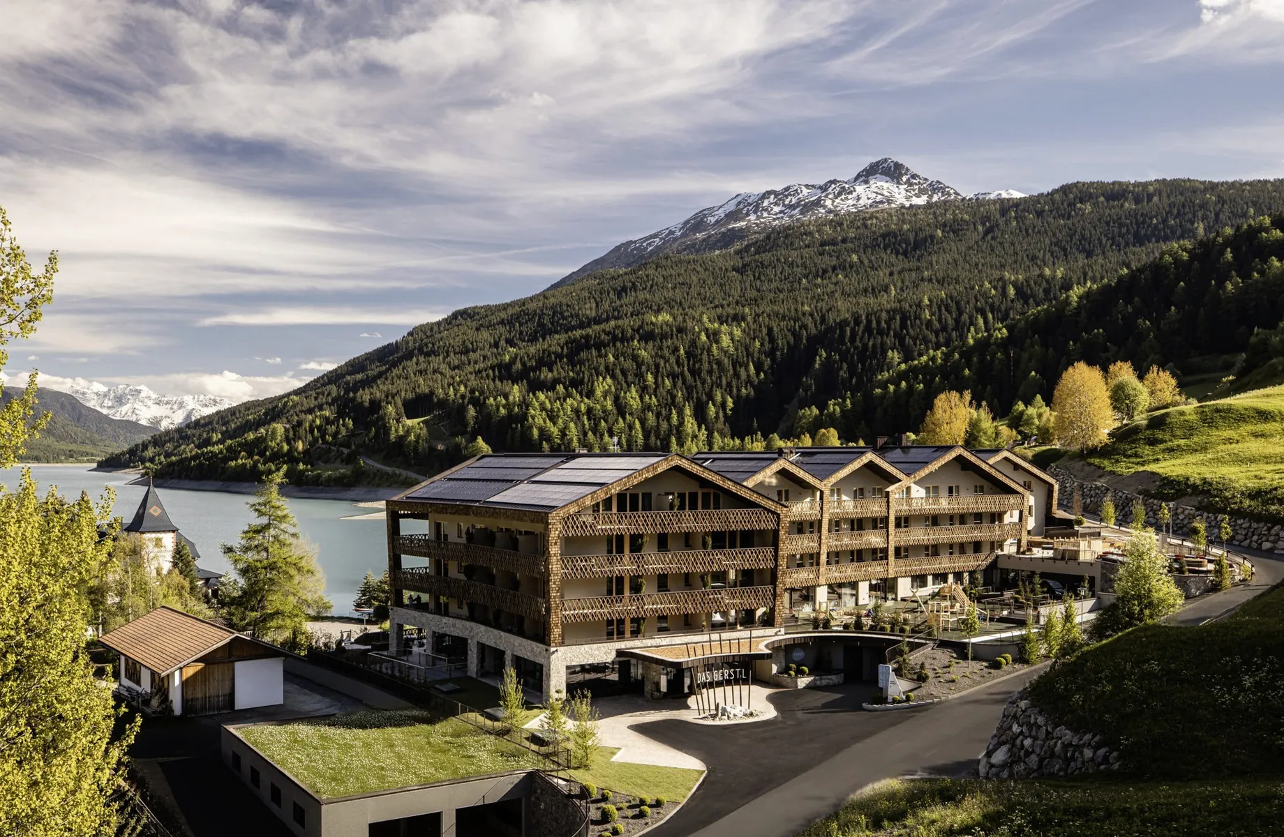 Außenansicht des DAS GERSTL Family Resort mit Blick auf den Reschensee