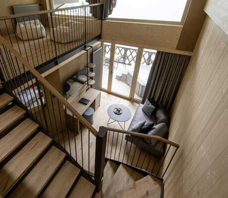Blick von oben auf die Treppe des Chalets mit Holzverkleidung im DAS GERSTL Family Resort