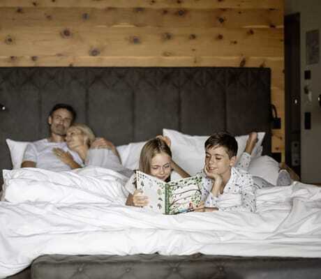 vierköpfige Familie im großen Doppelbett im DAS GERSTL Family Resort
