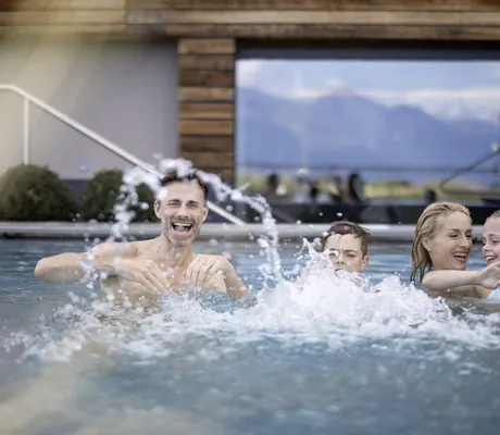 Familie mit zwei Kindern plantscht im Outdoorpool des DAS GERSTL Family Resort