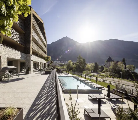 Blick auf die Fassede und den Outdoorpool des DAS GERSTL Family Resort direkt am Reschensee