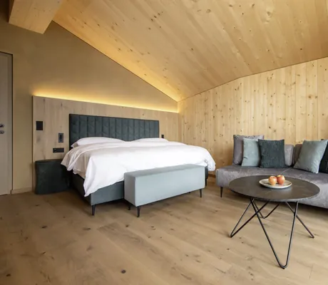 komplett mit Holz verkleidete Suite im DAS GERSTL Family Resort mit grau-olivgrünen Textilien