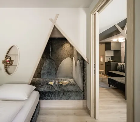 Kinderbereich im Hotelzimmer mit kleinem Bett und gemütlicher Leseecke in Form eines Tipis im Falkensteiner Family Resort Lido