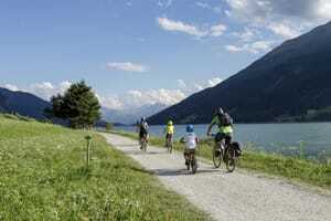 Familie fährt auf dem Radweg am Reschensee entlang