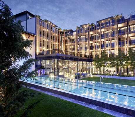 Außen-Schwimmbecken vor der beleuchteten Fassade des Wellnesshotel Jagdhof in der Abenddämmerung