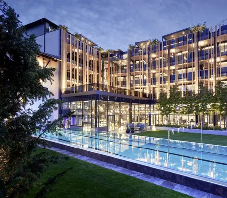 Außen-Schwimmbecken vor der beleuchteten Fassade des Wellnesshotel Jagdhof in der Abenddämmerung
