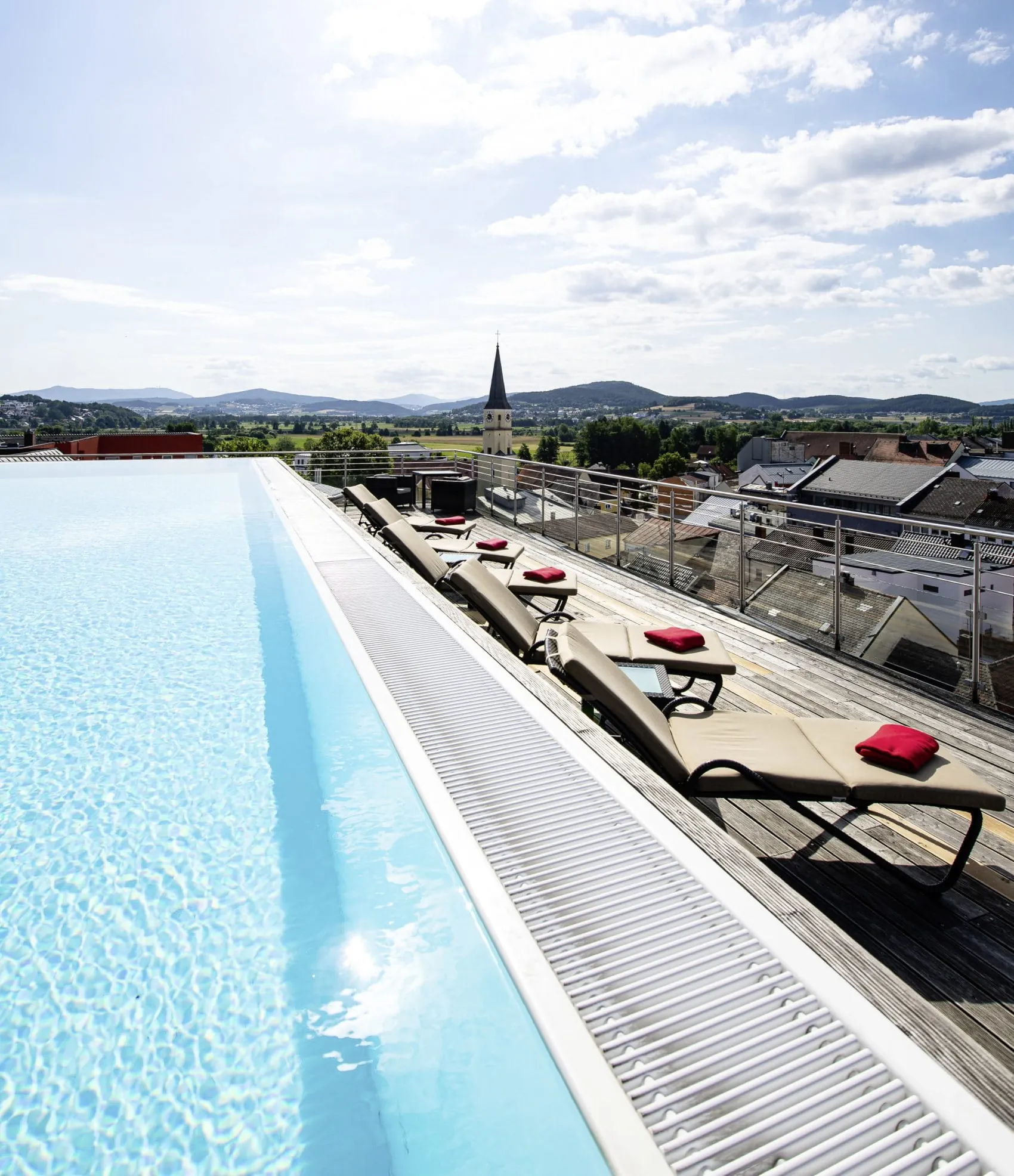 Skypool des Wellnesshotels Randsbergerhof auf Dachterrasse mit Liegestühlen und Blick auf Stadt Cham und Hügel