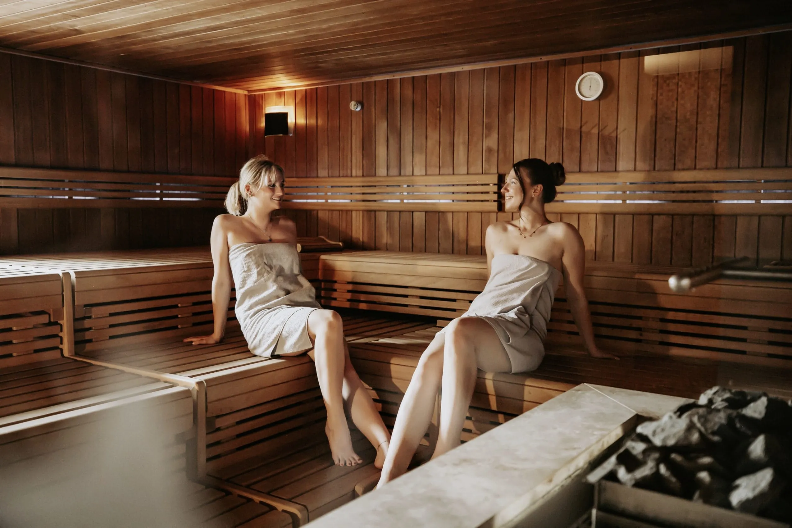 Zwei Frauen sitzen in einer Sauna des Wellnesshotels Randsbergerhof, jeweils in ein Handtuch gewickelt