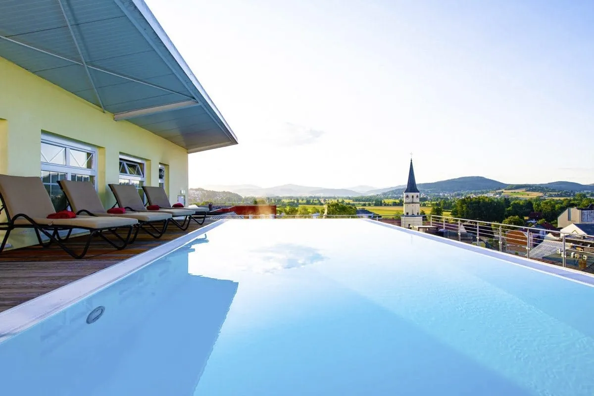 Skypool auf der Dachterrasse des Wellnesshotels Randsbergerhof mit Liegest&uuml;hlen und Blick auf Kirchturm und Landschaft