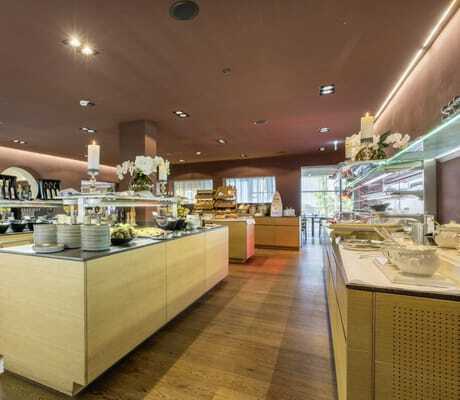 Buffetbereich mit mehreren Holzinseln, Tellerstapeln, Kerzen und Blumenarrangements im Hotel Schwarzbrunn