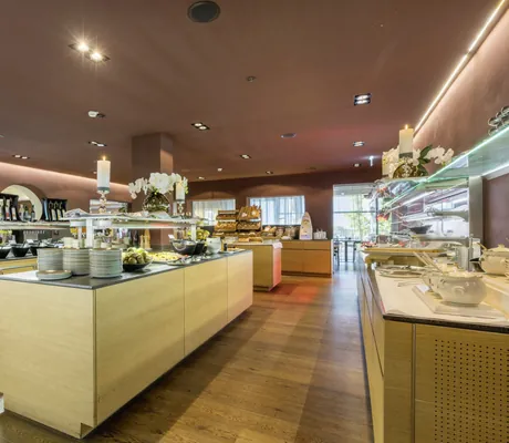 Buffetbereich mit mehreren Holzinseln, Tellerstapeln, Kerzen und Blumenarrangements im Hotel Schwarzbrunn