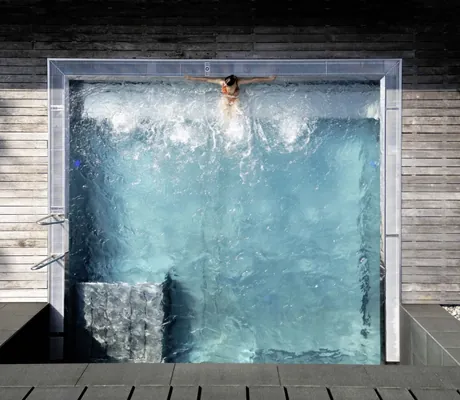 Luftaufnahme des Outdoorpools des Hotel Schwarzbrunn mit einer Frau, die im Pool am Beckenrand sitzt