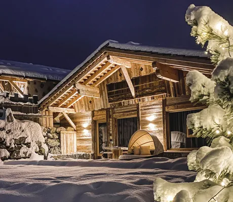 Außenansicht eines beleuchteten Chalets im Schnee am Abend im Chalet Resort ZU KIRCHWIES