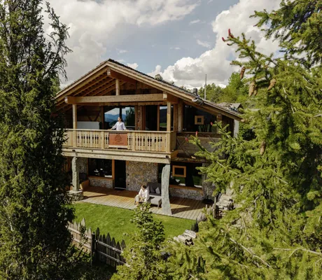 Zweistöckige Waldvilla des Chalet Resort ZU KIRCHWIES aus Holz und Stein mit Balkon und Terrasse, umgeben von Bäumen
