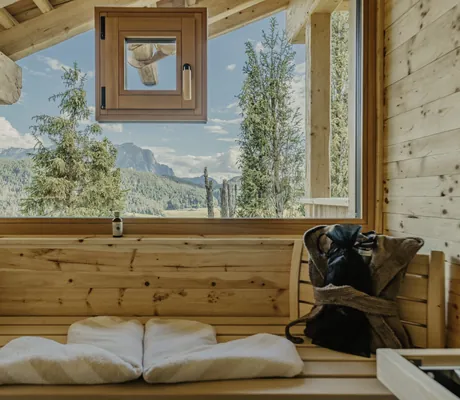 Holzsauna mit Fenster und Blick auf bewaldete Berge und Felsen, Aufgusseimer, Handtücher im Chalet Resort ZU KIRCHWIES