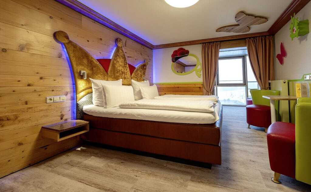 Junior Suite im Feldberger Hof mit Königskrone als Bett-Rückwand und rot-grünen Sesseln