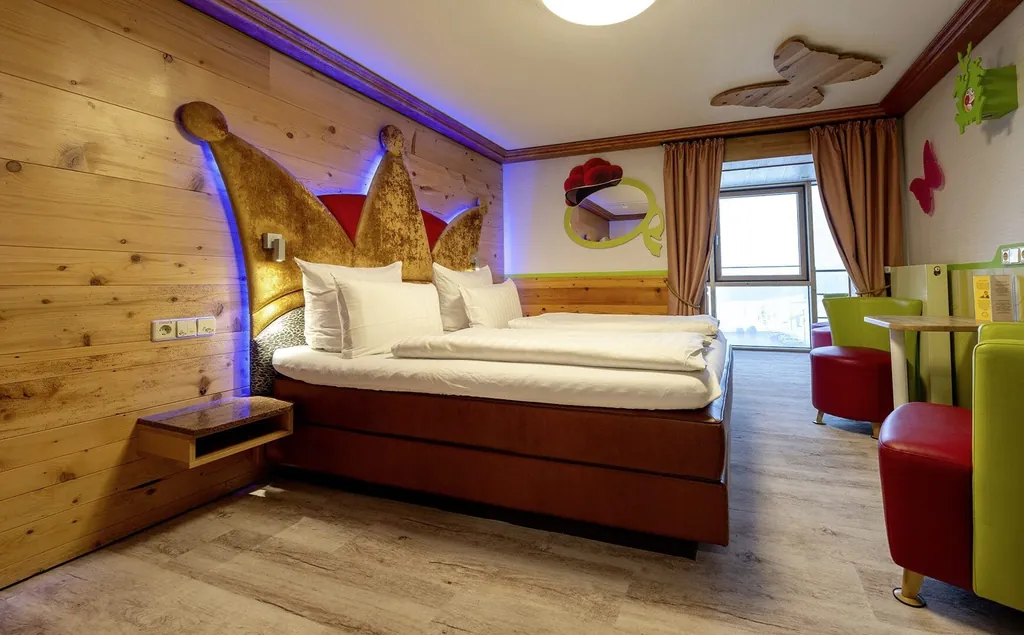Junior Suite im Feldberger Hof mit Königskrone als Bett-Rückwand und rot-grünen Sesseln