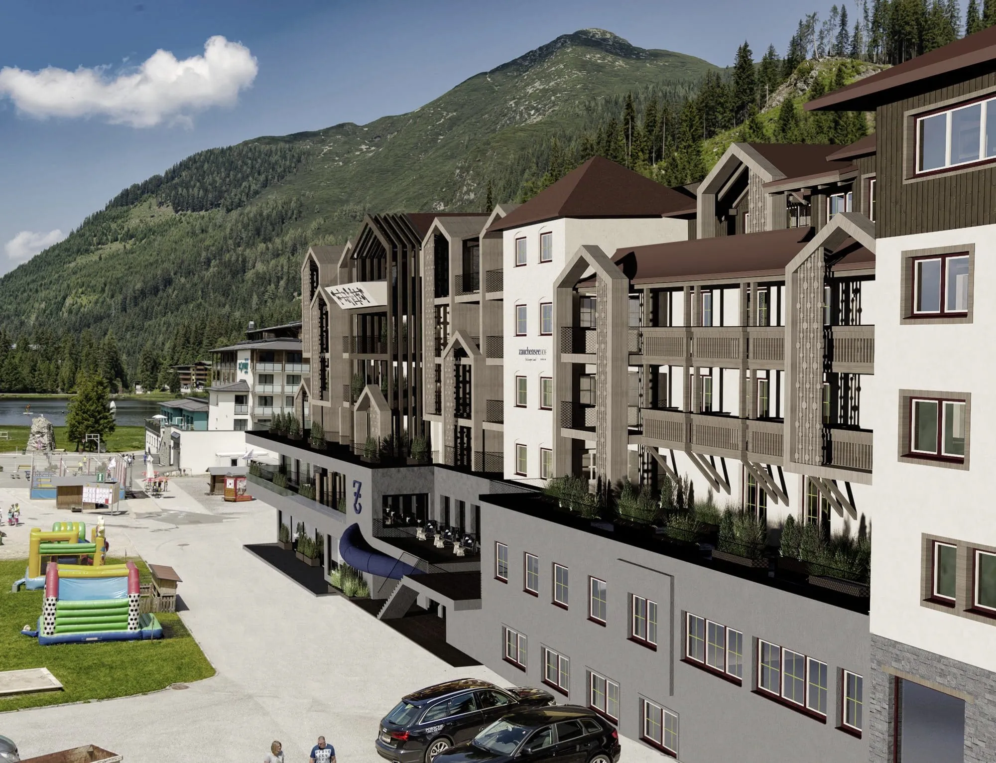 Außenansicht des Familotel Zauchenseehof im Sommer mit Bergkulisse, Hüpfburgen und Spielplatz