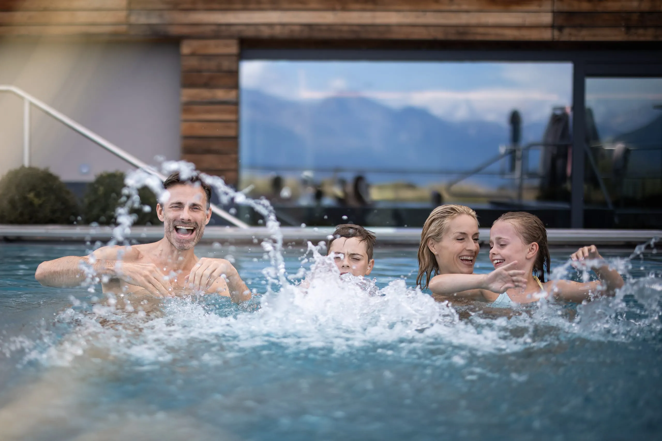 Familie mit Frau, Mann und zwei Kindern, ein Junge und ein Mädchen. planschen draußen im Pool.