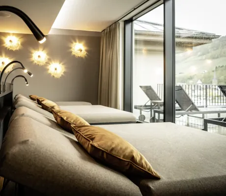 Ruheraum mit grauen Liegen und ockerfarbenen Kissen im Moselschlösschen Spa & Resort