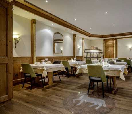 Restaurant im Hotel Lamm mit eingedeckten Tischen, grünen Stühlen und Kachelofen