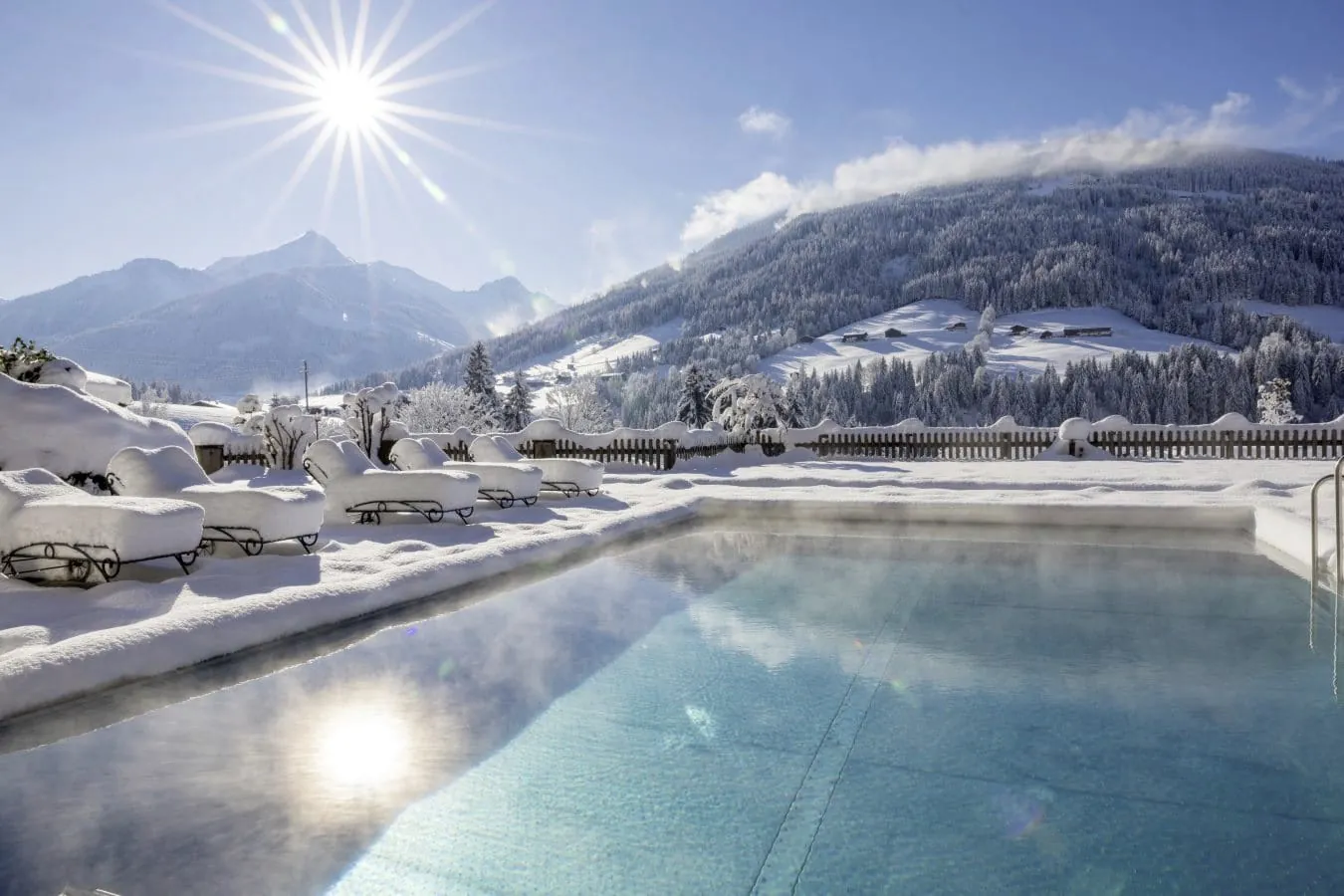 eingeschneite Liegen am Oitdoorpool im Alpbacherhof im tiefen Winter