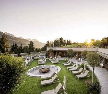 Sonnenliegen platziert an runder Feuerstelle im Spabereich des Alpen Tesitin