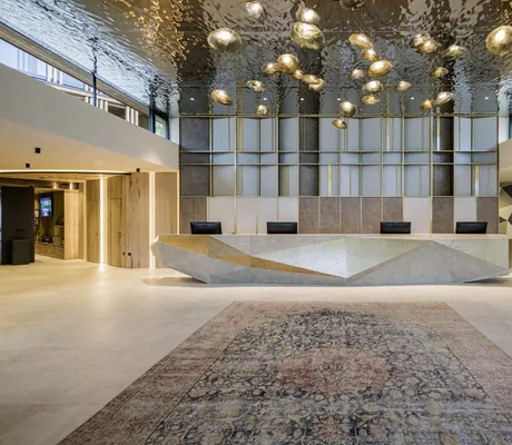 riesige Lobby im Alpen Tesitin mit großer silberner Theke und goldenen runden Lampen