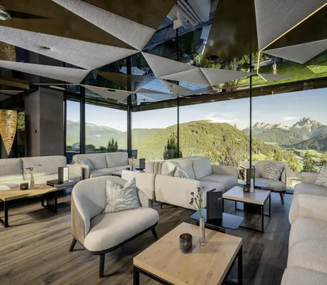 Panoramablick auf die Dolomiten von der Lounge des Alpen Tesitin mit weißen Polstermöbeln aus