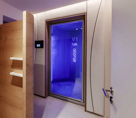 beleuchteter Eingang der Kältekammer im Alpenresort Schwarz mit Holzregalen davor