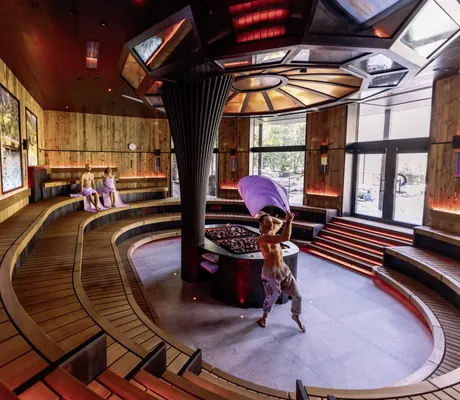 Saunameister schwingt Handtuch im der großen runden Sauna mit Videowänden im Andreus Resort