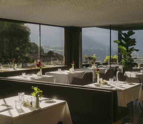 gedeckte Tische im Restaurant des Avidea mit Panoramablick auf Meran